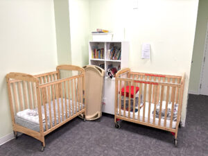 Two wooden children’s beds in a room with a white bookshelf filled with children’s books