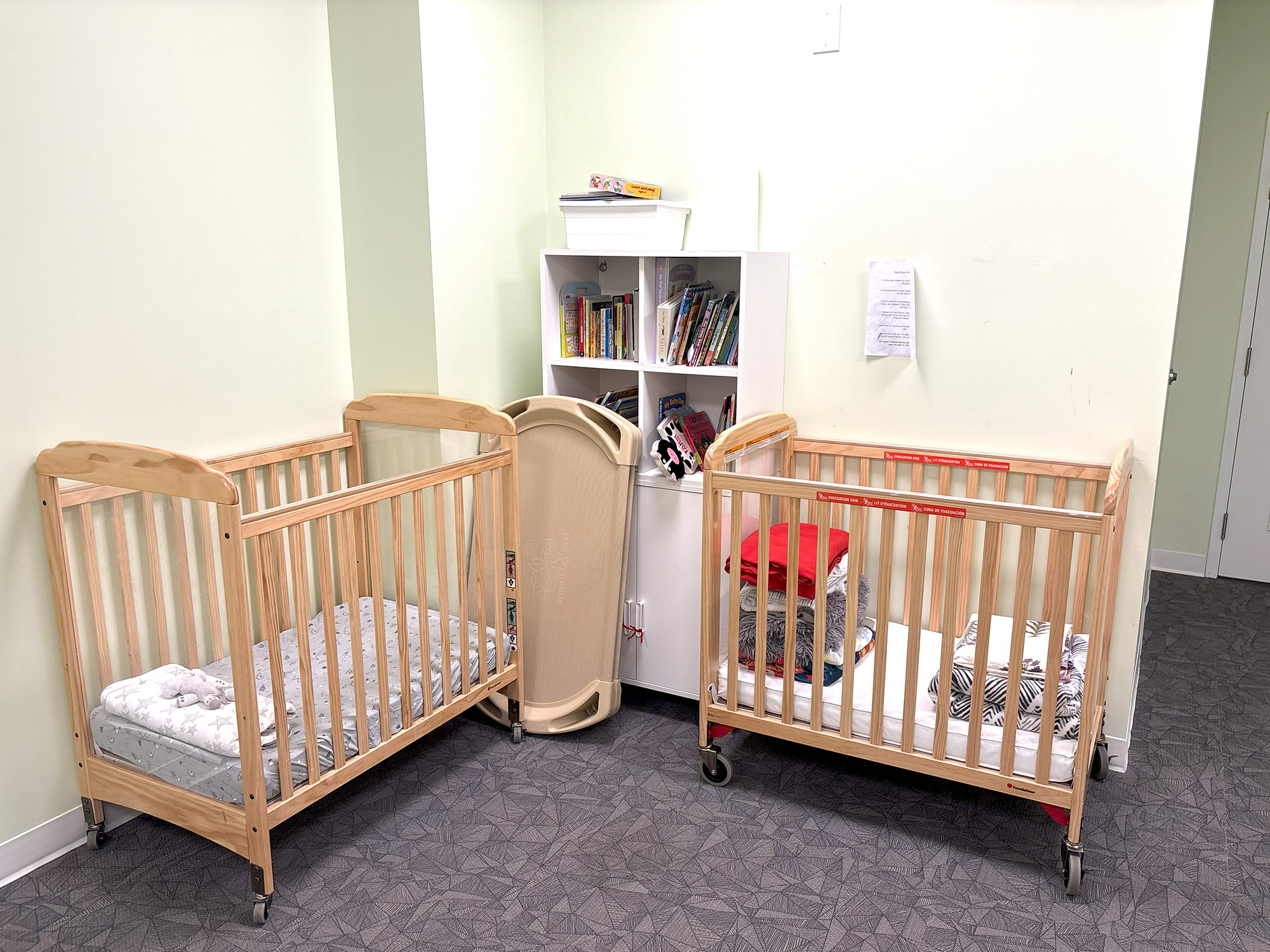 Two wooden children’s beds in a room with a white bookshelf filled with children’s books