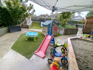A playground area in front of a building with a slide and several tricycles